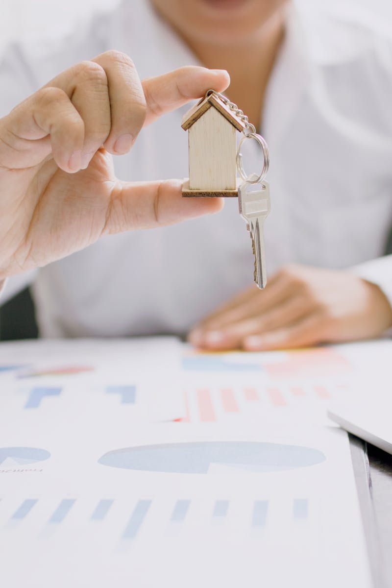Real estate professional presenting a house model with keys, symbolizing property investment and ownership.