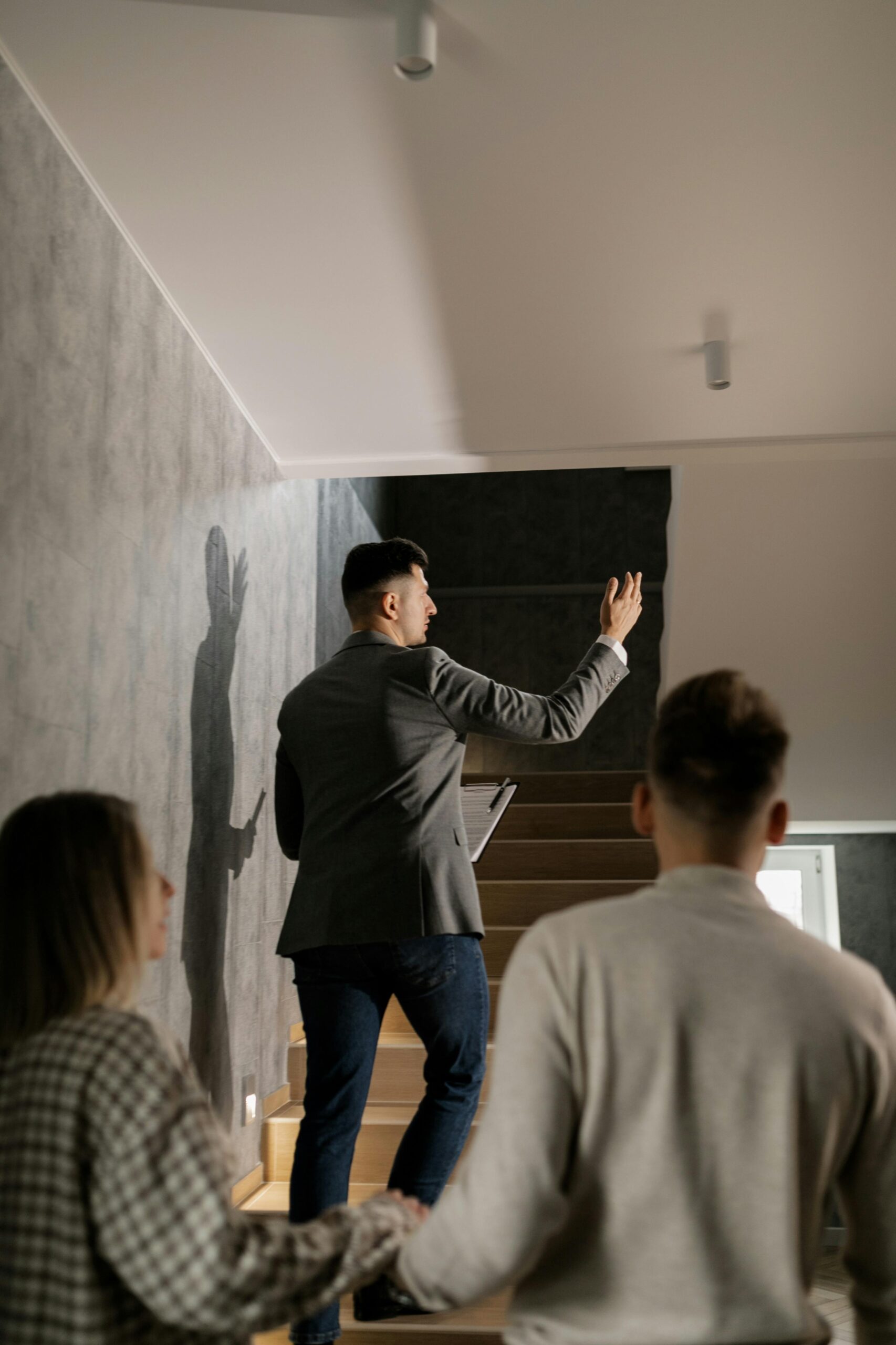 A real estate agent leads a couple on a house tour, highlighting interior features in a modern home.